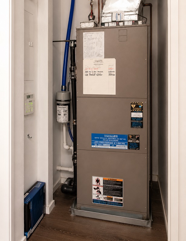 Residential gas furnace installed in a utility closet with ductwork and air filtration system